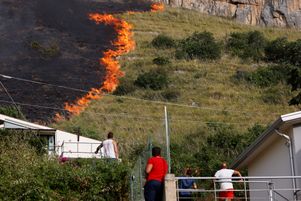 Des habitants observent les flammes à Capaci, près de Palerme, en Sicile, le mercredi 26 juillet 2023.