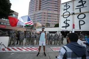 Un homme brandit un drapeau aux couleurs des États-Unis et du Mexique devant des membres de la Garde nationale, à Los Angeles (Californie), le 12 juin 2025